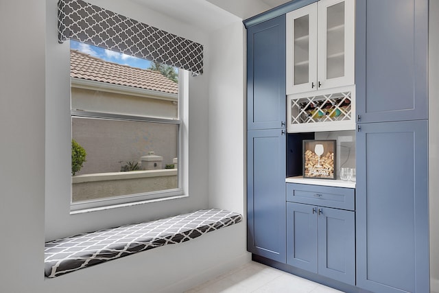 bar with light tile patterned flooring and blue cabinetry