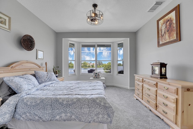 bedroom with light colored carpet and a textured ceiling