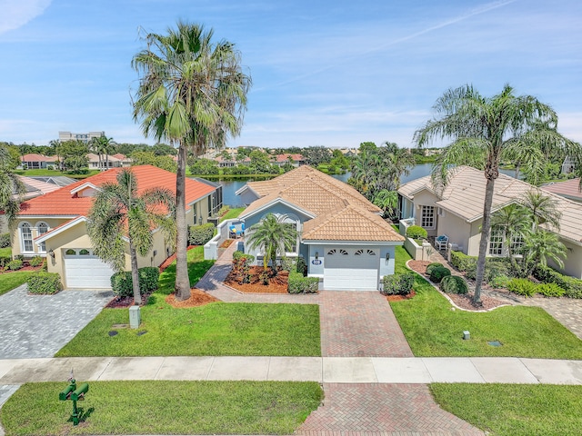 mediterranean / spanish home featuring a front yard, a water view, and a garage