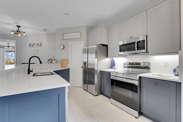 kitchen with an inviting chandelier, sink, gray cabinets, light tile patterned floors, and appliances with stainless steel finishes