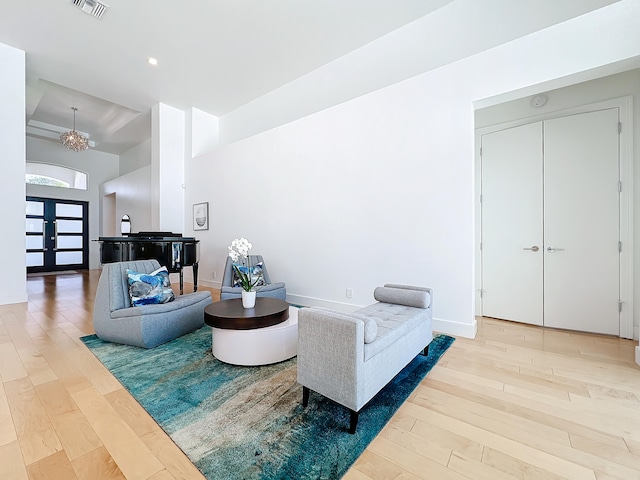 living room featuring a chandelier, hardwood / wood-style flooring, and french doors