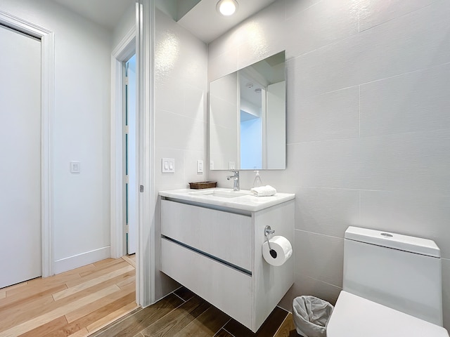 bathroom with tile walls, vanity, hardwood / wood-style floors, and toilet