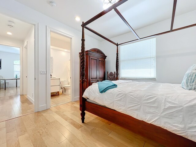 bedroom featuring connected bathroom and light hardwood / wood-style floors