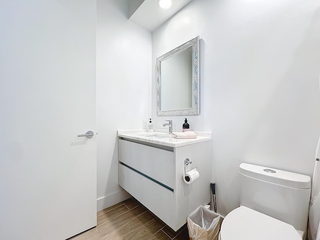 bathroom with wood-type flooring, vanity, and toilet