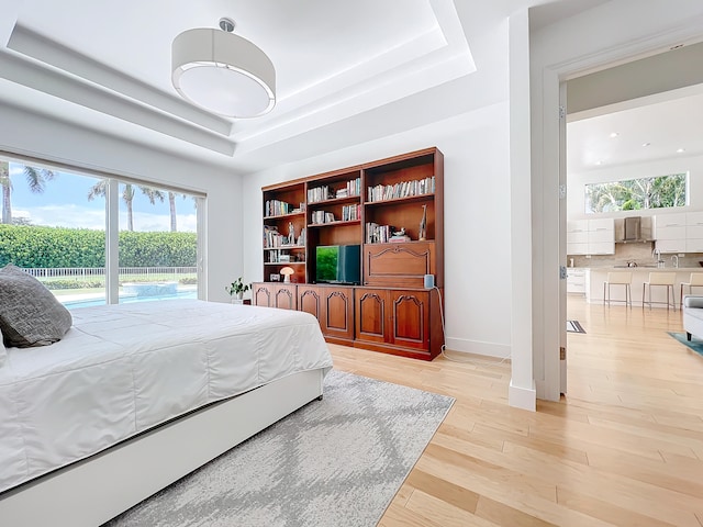 bedroom featuring light hardwood / wood-style flooring and a raised ceiling