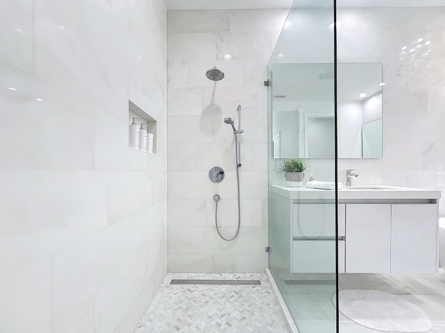 bathroom with a tile shower and vanity