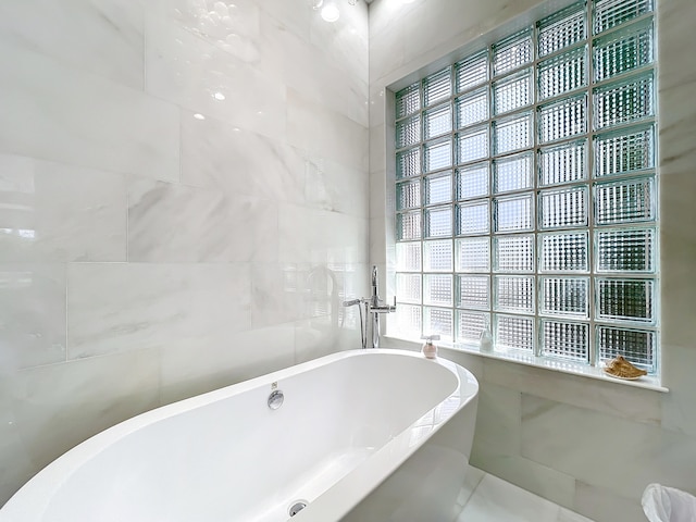 bathroom featuring tile walls, a wealth of natural light, and a tub