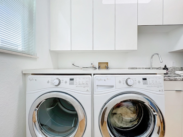 clothes washing area with cabinets and washing machine and dryer