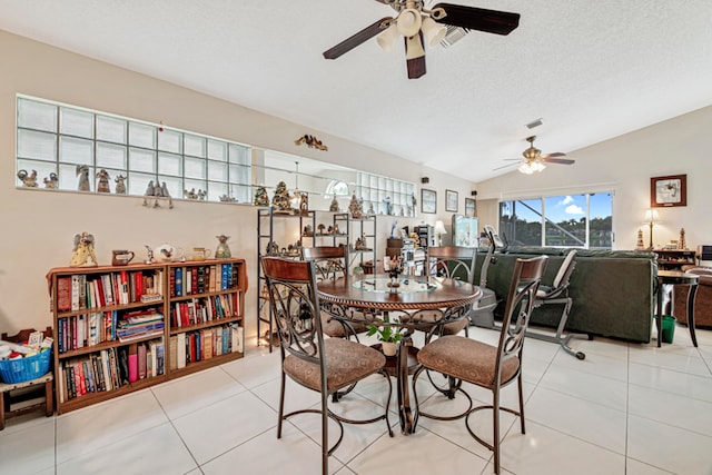 tiled dining space with ceiling fan, a textured ceiling, and lofted ceiling