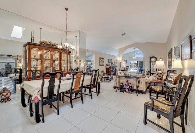 tiled dining room with ceiling fan and lofted ceiling with skylight