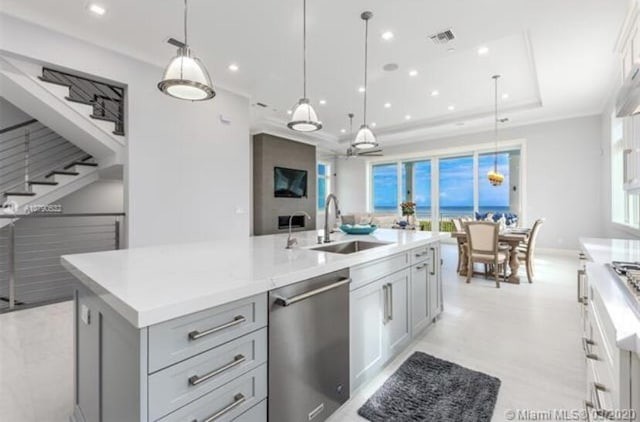 kitchen with visible vents, a raised ceiling, dishwasher, a sink, and a kitchen island with sink