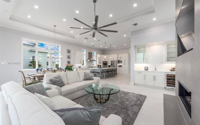 living room featuring ceiling fan, a high end fireplace, wine cooler, and a tray ceiling