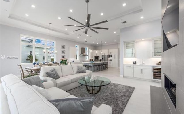 living area featuring a raised ceiling, beverage cooler, and recessed lighting