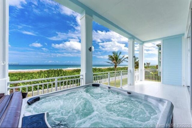 balcony with a water view and an outdoor hot tub