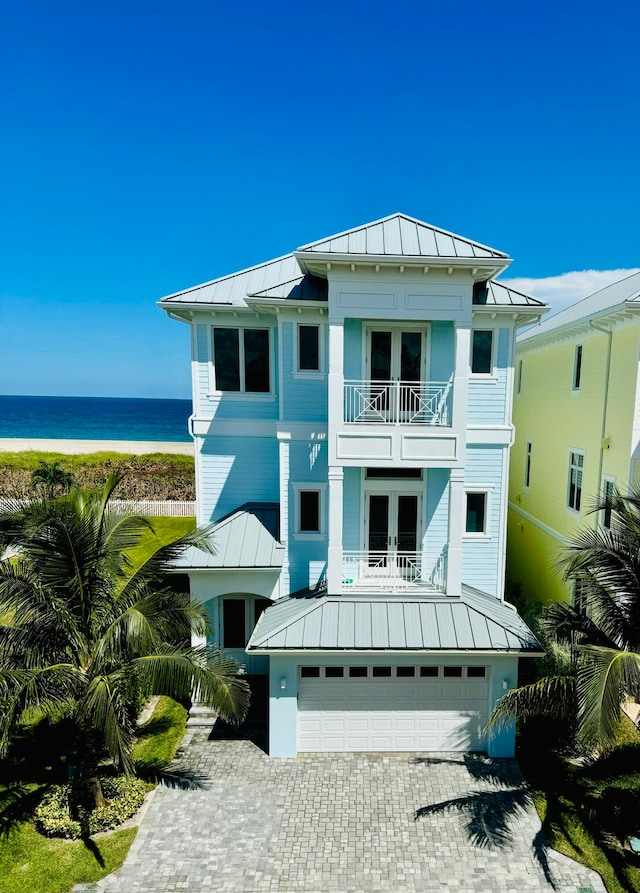 back of house featuring a water view, a garage, and a balcony