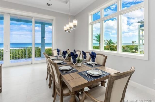 dining space with a water view, a wealth of natural light, baseboards, and an inviting chandelier