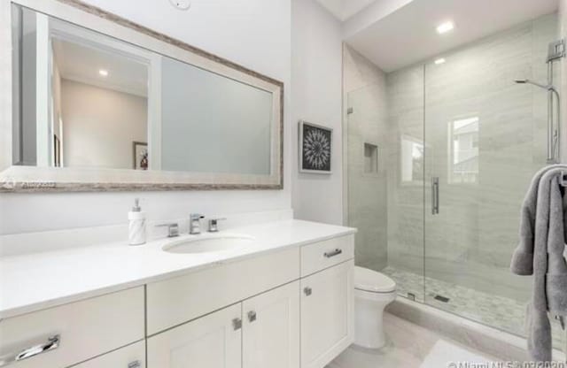 bathroom with walk in shower, vanity, and toilet