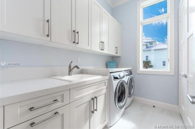 washroom featuring a sink, baseboards, cabinet space, and washer and dryer