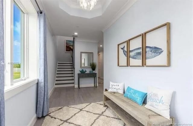 hallway with wood finished floors, baseboards, ornamental molding, and stairway