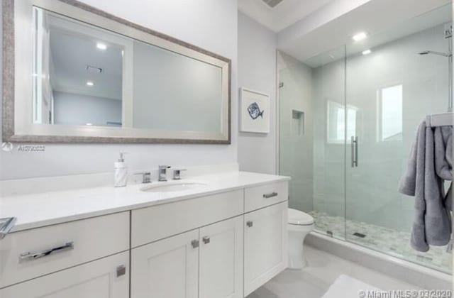 bathroom featuring toilet, a stall shower, and vanity