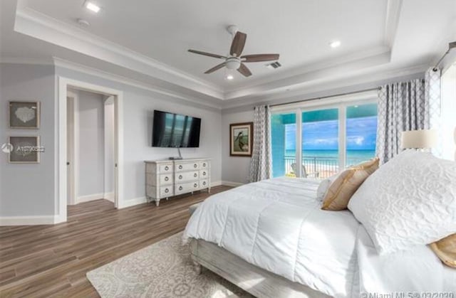 bedroom featuring ceiling fan, a raised ceiling, ornamental molding, dark hardwood / wood-style floors, and access to exterior