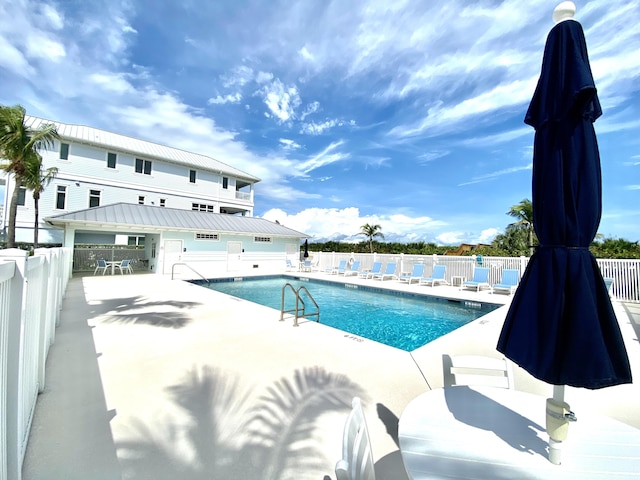 community pool with a patio area and fence