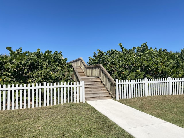 obstructed view of property with a front yard, fence, and stairs