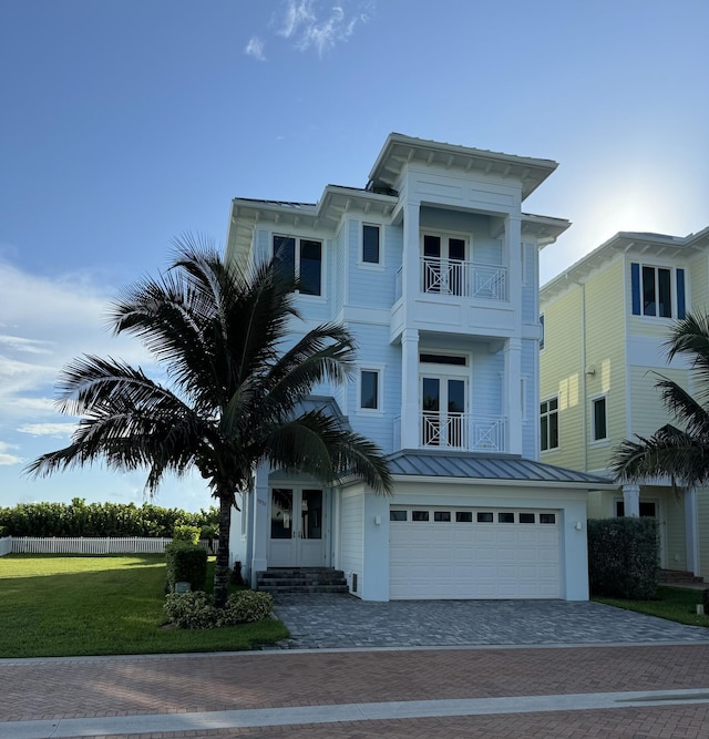 view of front facade featuring entry steps, a garage, a balcony, french doors, and a standing seam roof