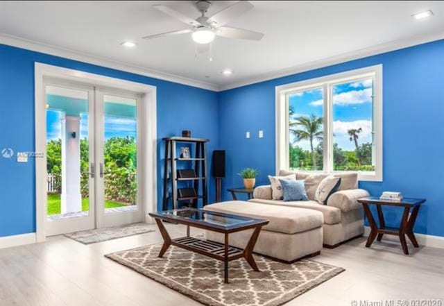 living room featuring ornamental molding, light wood-type flooring, and ceiling fan