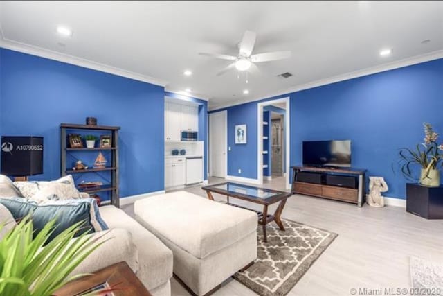 living room with ornamental molding, baseboards, and visible vents