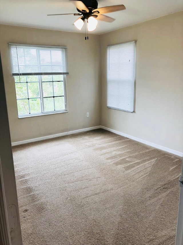 carpeted spare room with ceiling fan