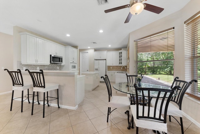 kitchen featuring ceiling fan, white cabinets, light tile patterned flooring, white appliances, and backsplash