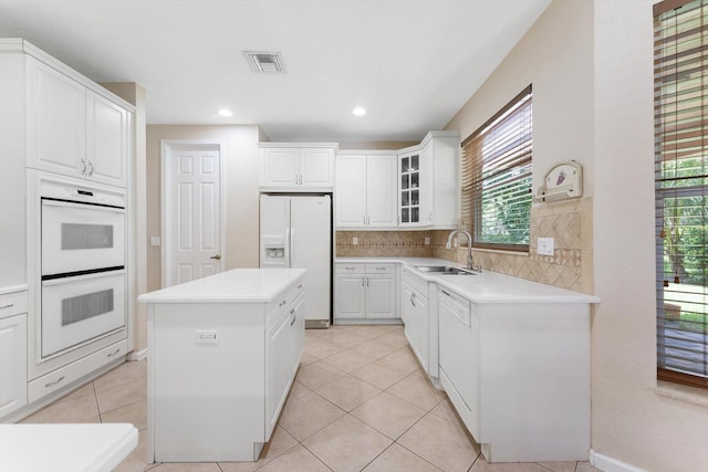 kitchen featuring a center island, sink, white cabinets, white appliances, and backsplash