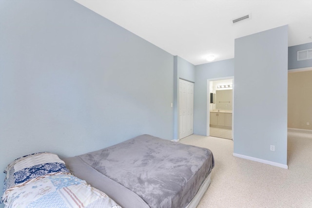 bedroom with light colored carpet, ensuite bathroom, and a closet