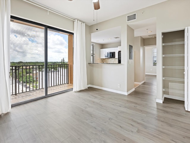 unfurnished living room featuring ceiling fan and light wood-type flooring