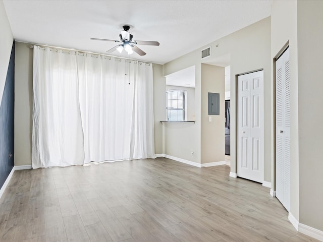 spare room with ceiling fan, electric panel, and light hardwood / wood-style flooring