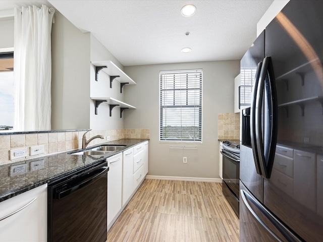 kitchen featuring sink, dark stone counters, decorative backsplash, white cabinets, and black appliances