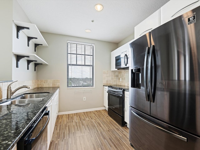 kitchen with sink, backsplash, dark stone countertops, white cabinets, and appliances with stainless steel finishes