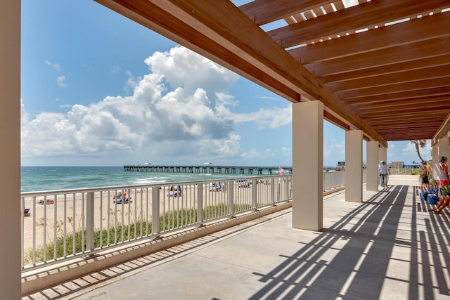 view of patio featuring a water view and a beach view