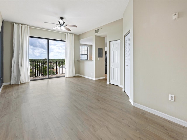 spare room with electric panel, ceiling fan, and light wood-type flooring