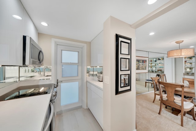 kitchen featuring hanging light fixtures, white range with electric stovetop, light carpet, and white cabinetry