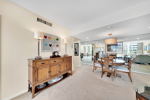 carpeted dining room featuring a textured ceiling