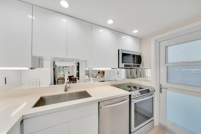 kitchen with appliances with stainless steel finishes, white cabinetry, and sink