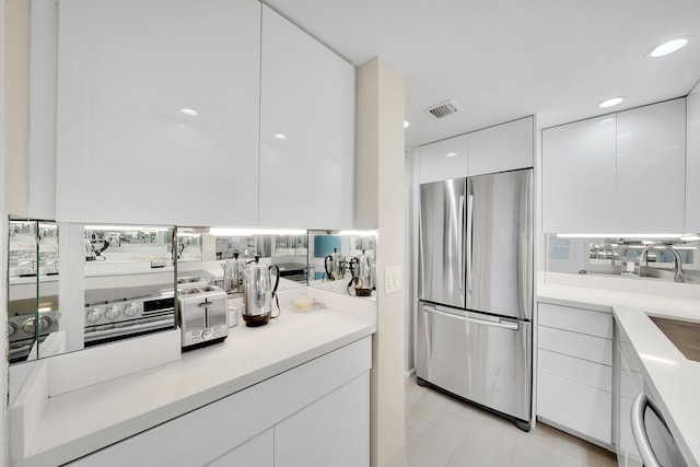 kitchen featuring dishwasher, stainless steel refrigerator, and white cabinets