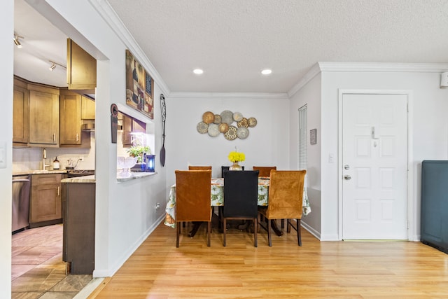 dining room with a textured ceiling, crown molding, and light hardwood / wood-style floors