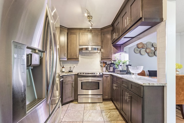 kitchen featuring appliances with stainless steel finishes, tasteful backsplash, light stone countertops, and dark brown cabinetry