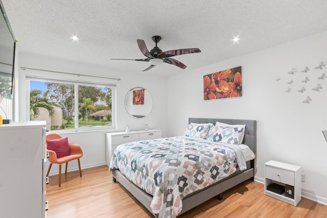 bedroom with ceiling fan, light hardwood / wood-style floors, and a textured ceiling