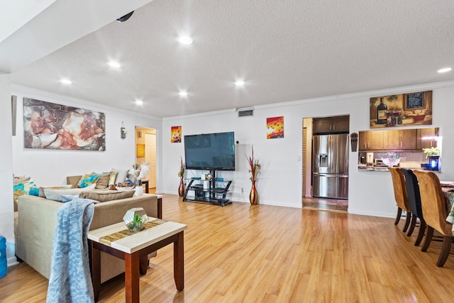 living room featuring a textured ceiling, crown molding, and light hardwood / wood-style flooring