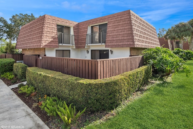 view of side of property with a lawn and a balcony