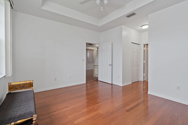 interior space with a raised ceiling, dark hardwood / wood-style flooring, and ceiling fan